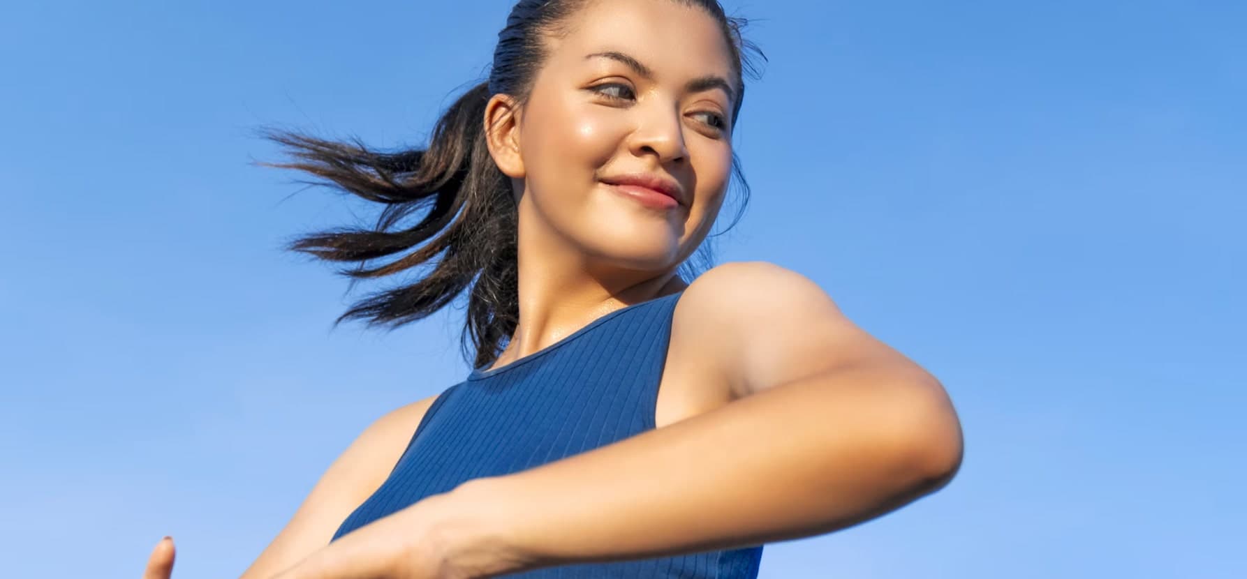 A smiling woman holds her hand out, showcasing the benefits of Vitamin B12 for healthier, radiant skin.