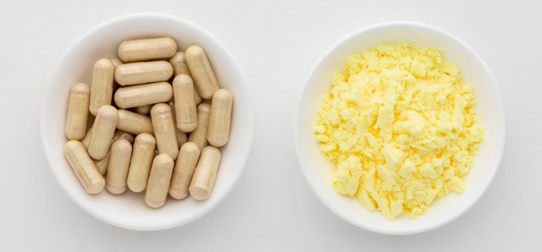 Image of two bowls containing pills and yellow powder, showcasing Alpha-Lipoic Acid for enhancing skin texture and tone.