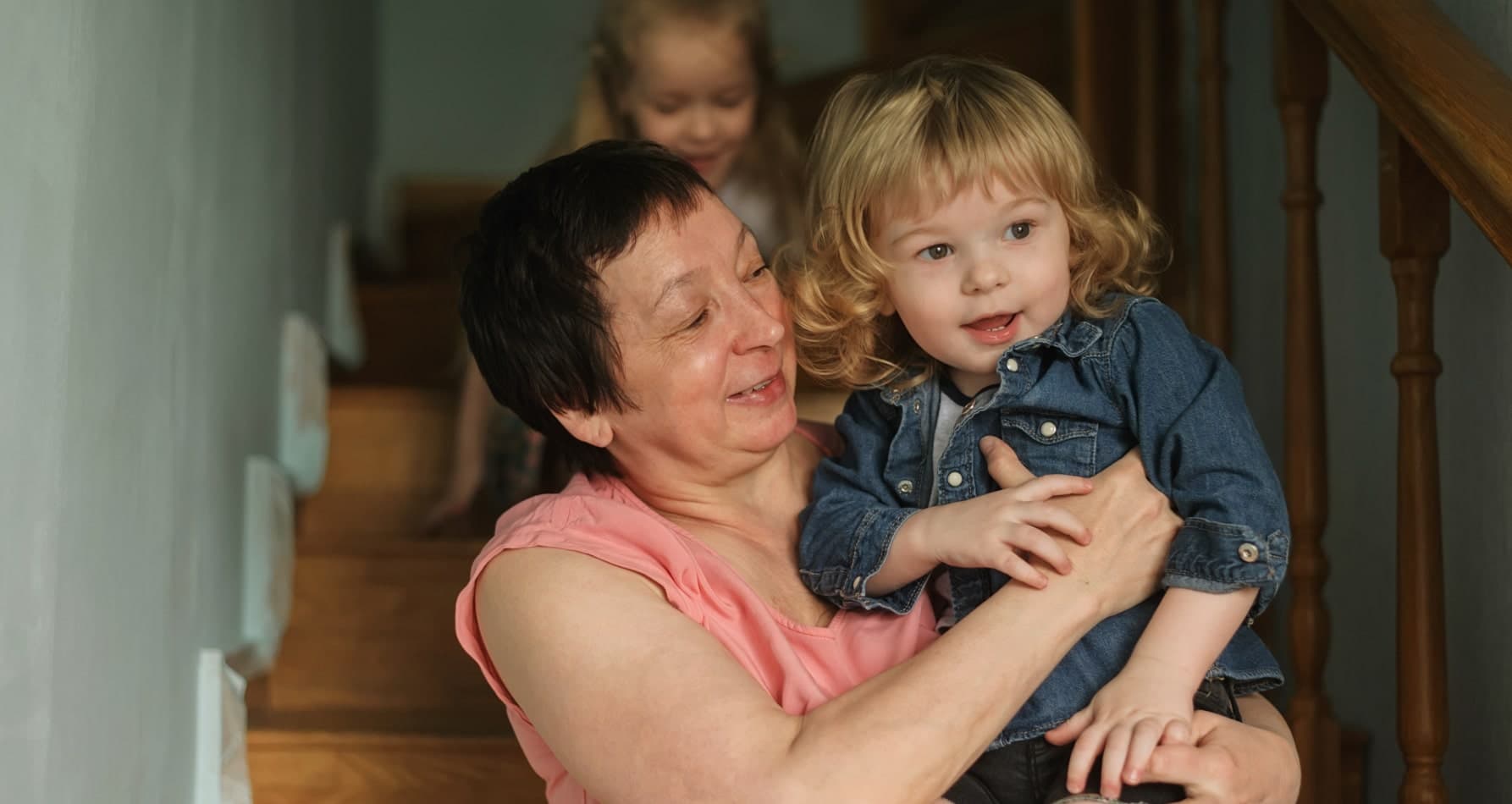 A woman gently holds a child on the stairs, showcasing the caring nature of professional nanny services.