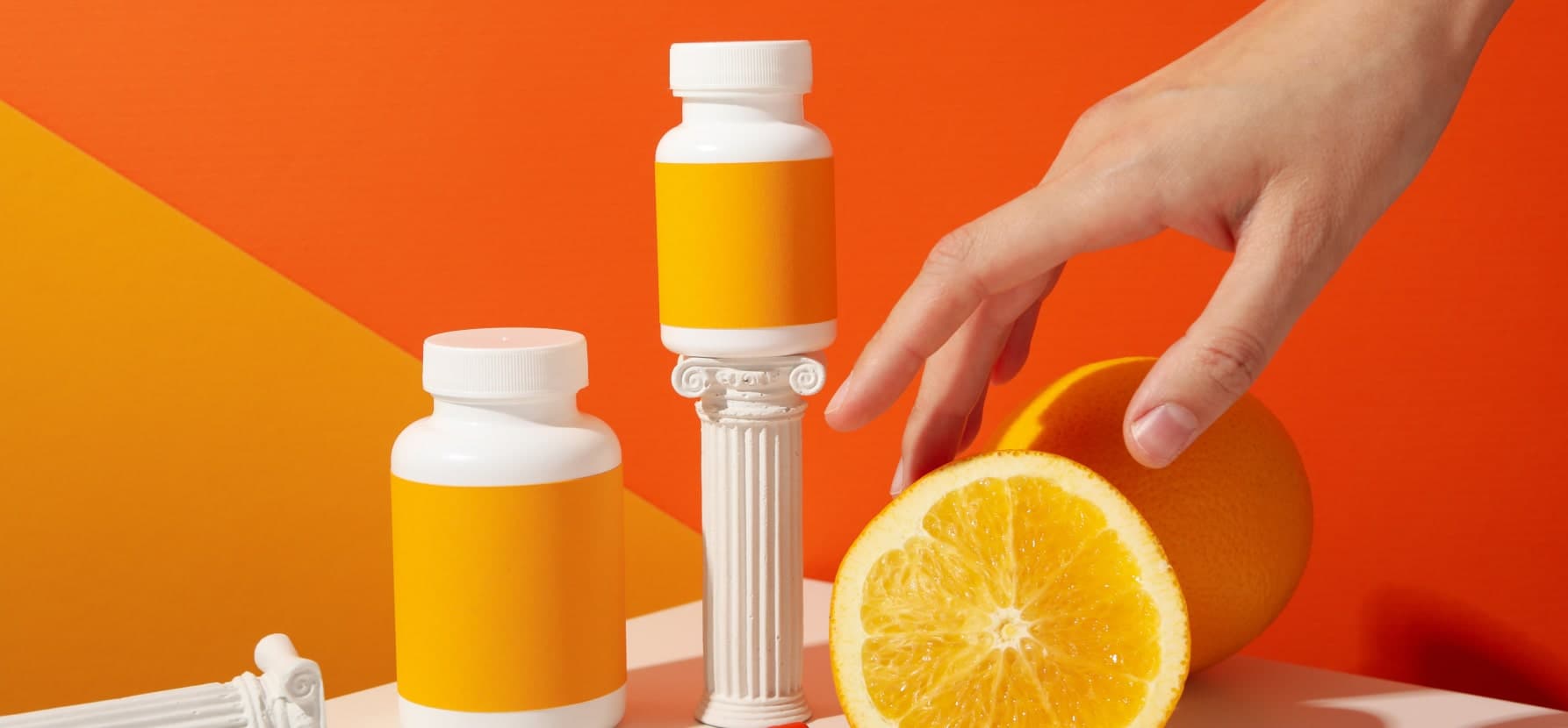 A hand grabbing a bottle of orange juice, featuring vitamin C gummies.