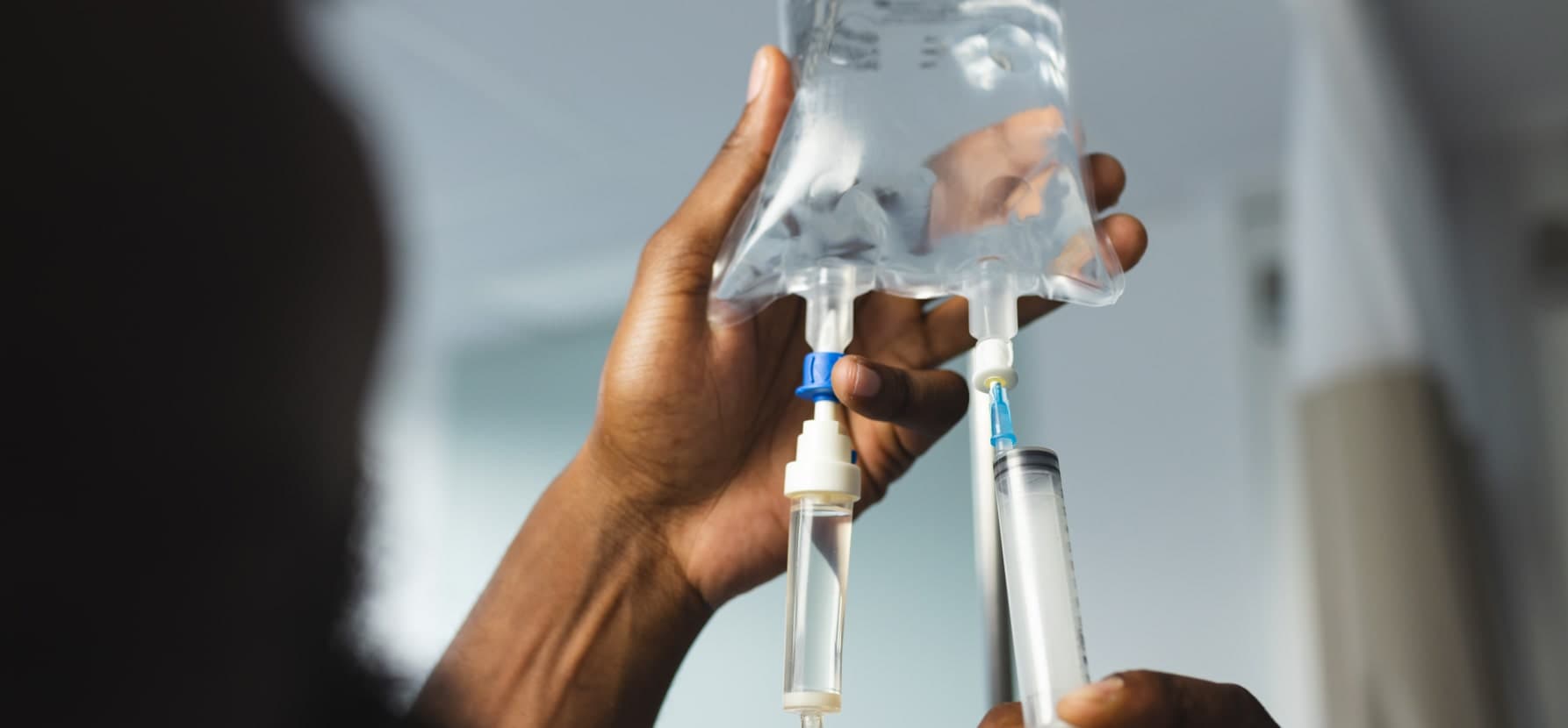 A nurse holding a syringe with a bag of IV drip.